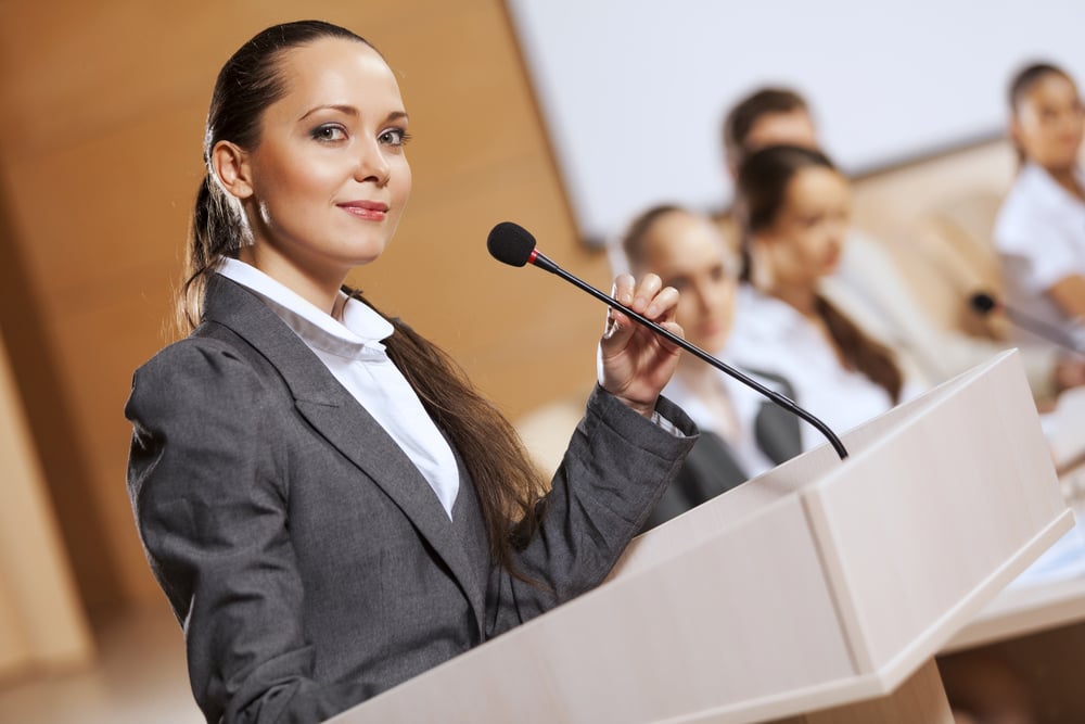 Businesswoman standing on stage and reporting for audience