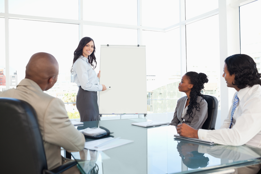 Young businesswoman giving a presentation while her colleagues are listening to her-1